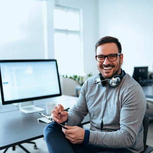IT Specialist Smiling and Working on Computer